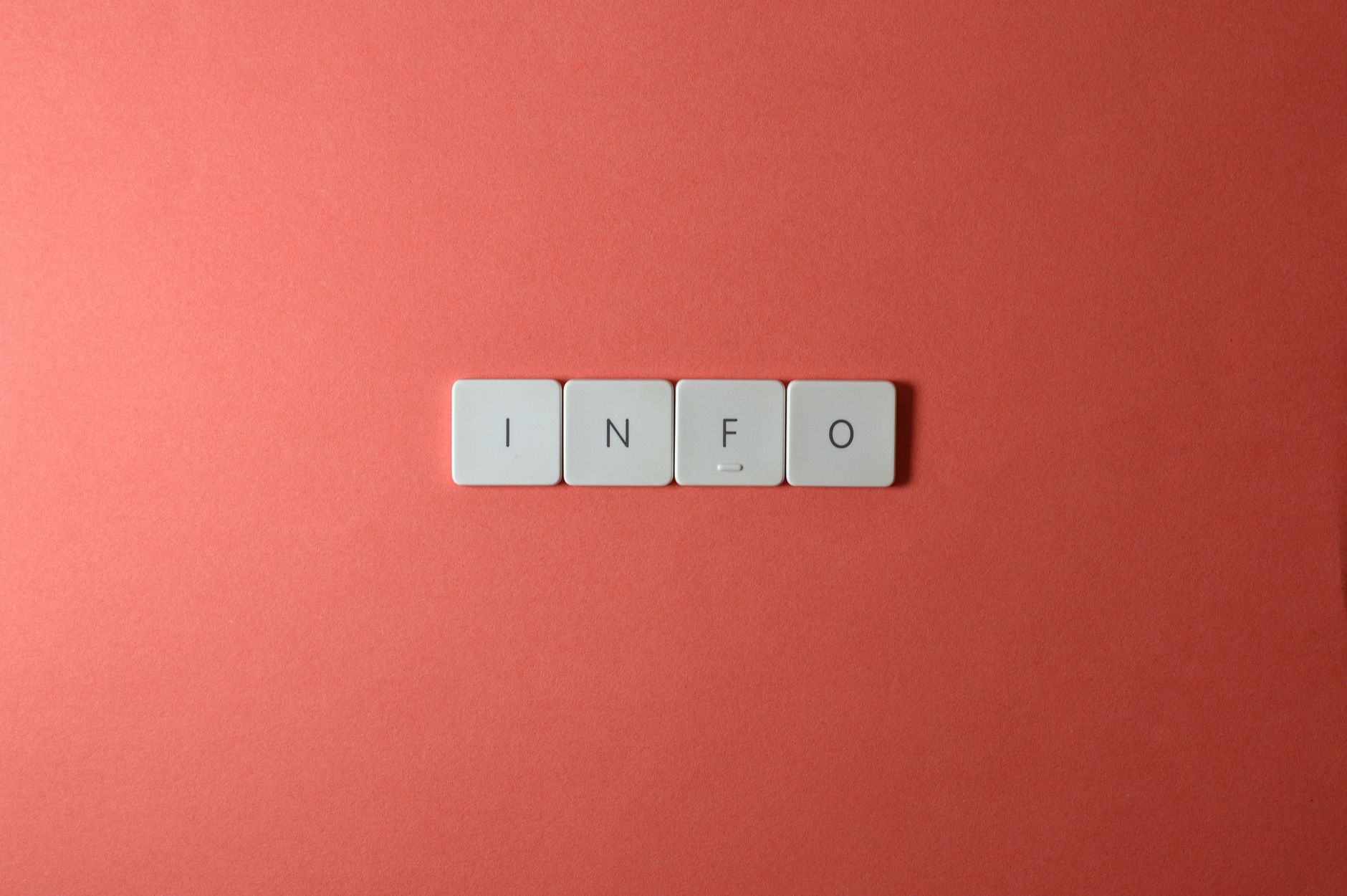 Close-up of keyboard buttons spelling 'INFO' on a minimal red background, ideal for tech and communication themes.