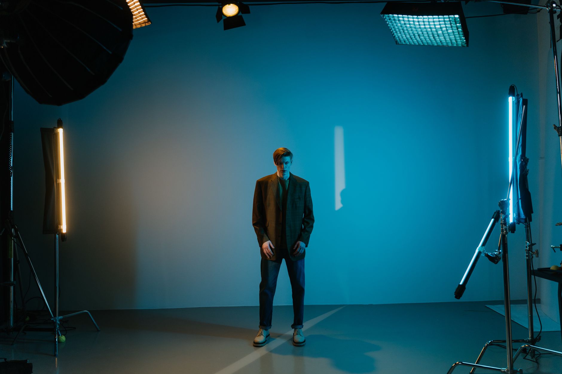 Portrait of a stylish man posing in a neon-lit studio with modern fashion.