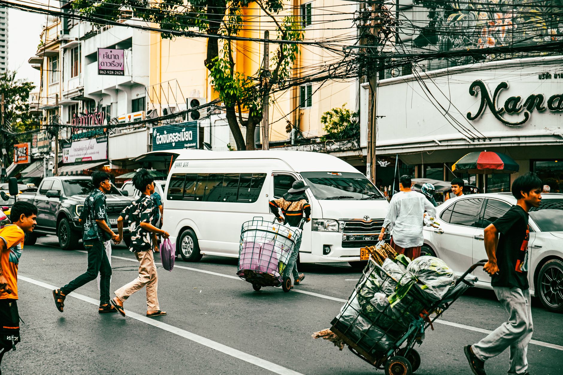 People crossing a bustling street in Bangkok, showcasing daily urban life and local culture.