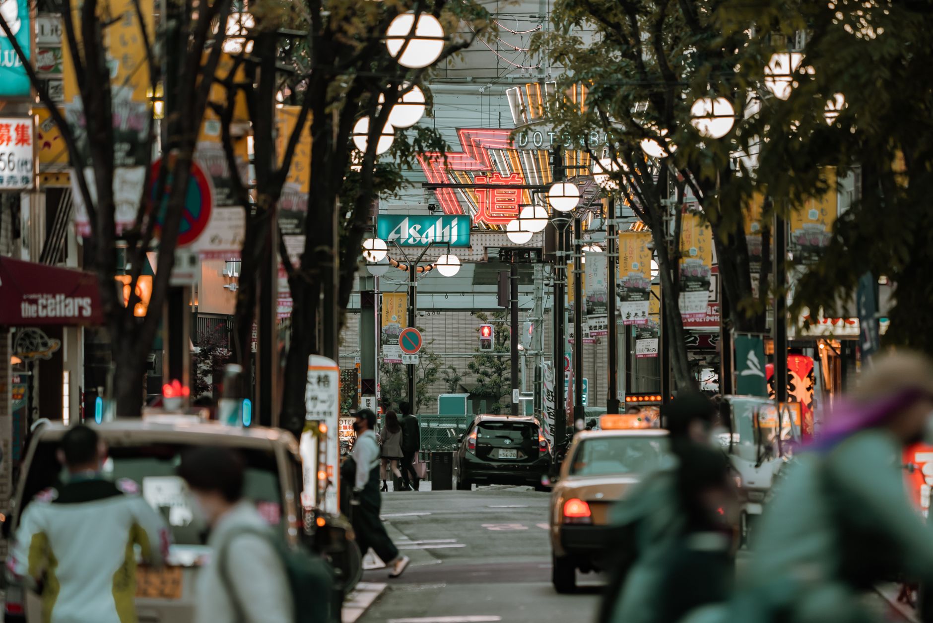 Vibrant Osaka street scene with signs and traffic during dusk, showcasing city life.