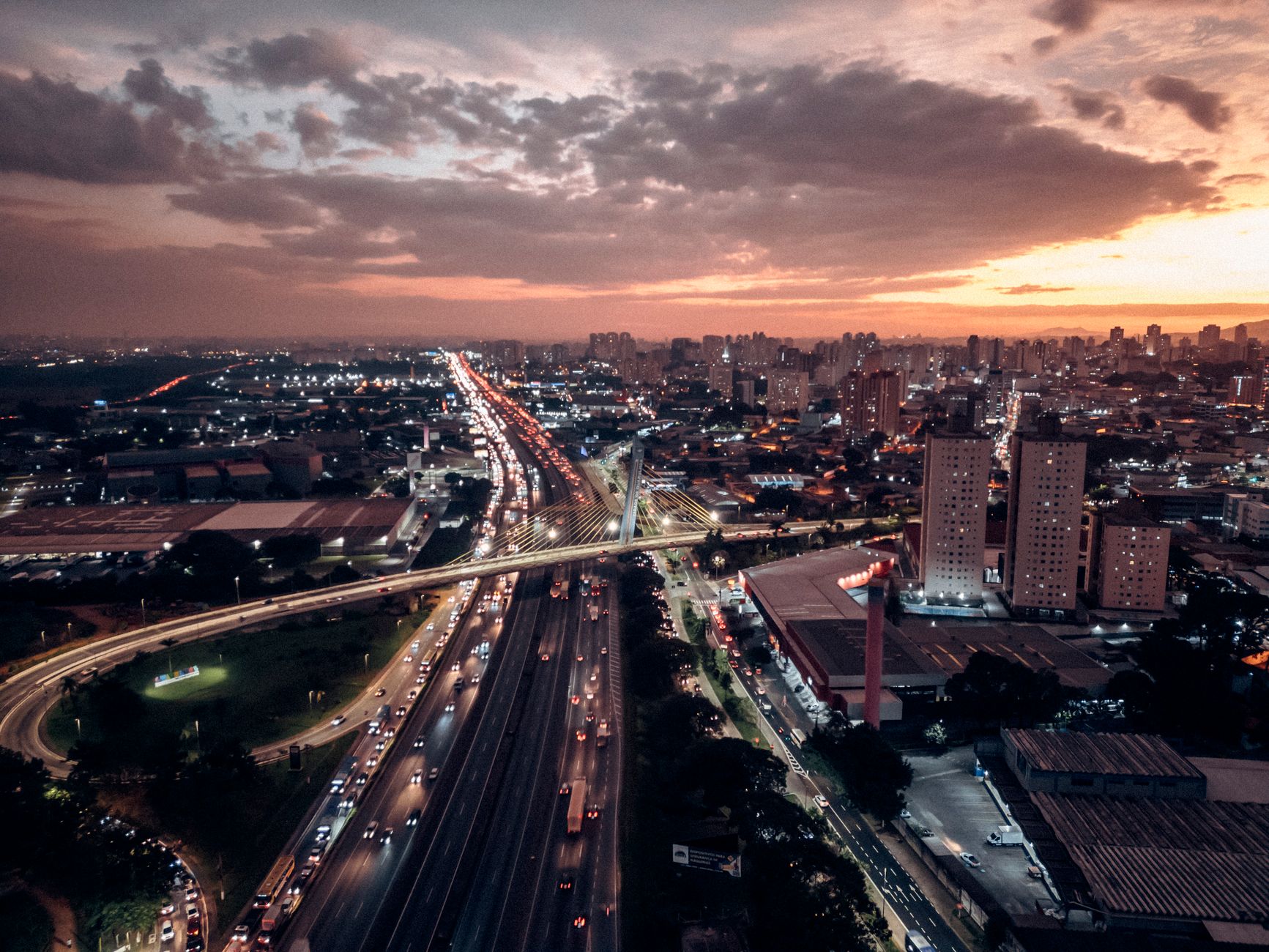 Breathtaking aerial view of Macedo, Brazil at sunset with bustling traffic and illuminated skyline.