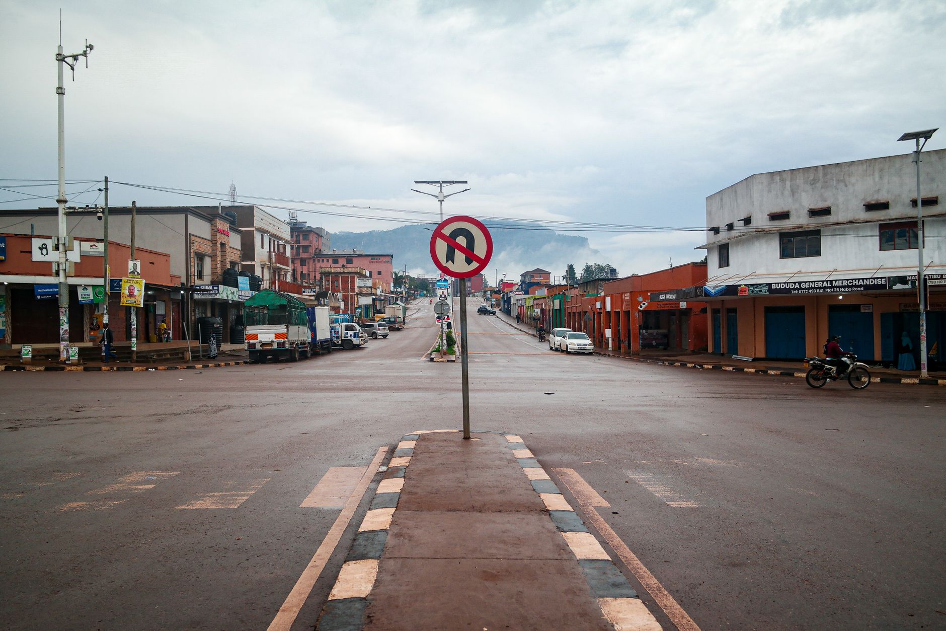 A calm street view in Mbale, Uganda, featuring urban architecture and a no-U-turn sign.