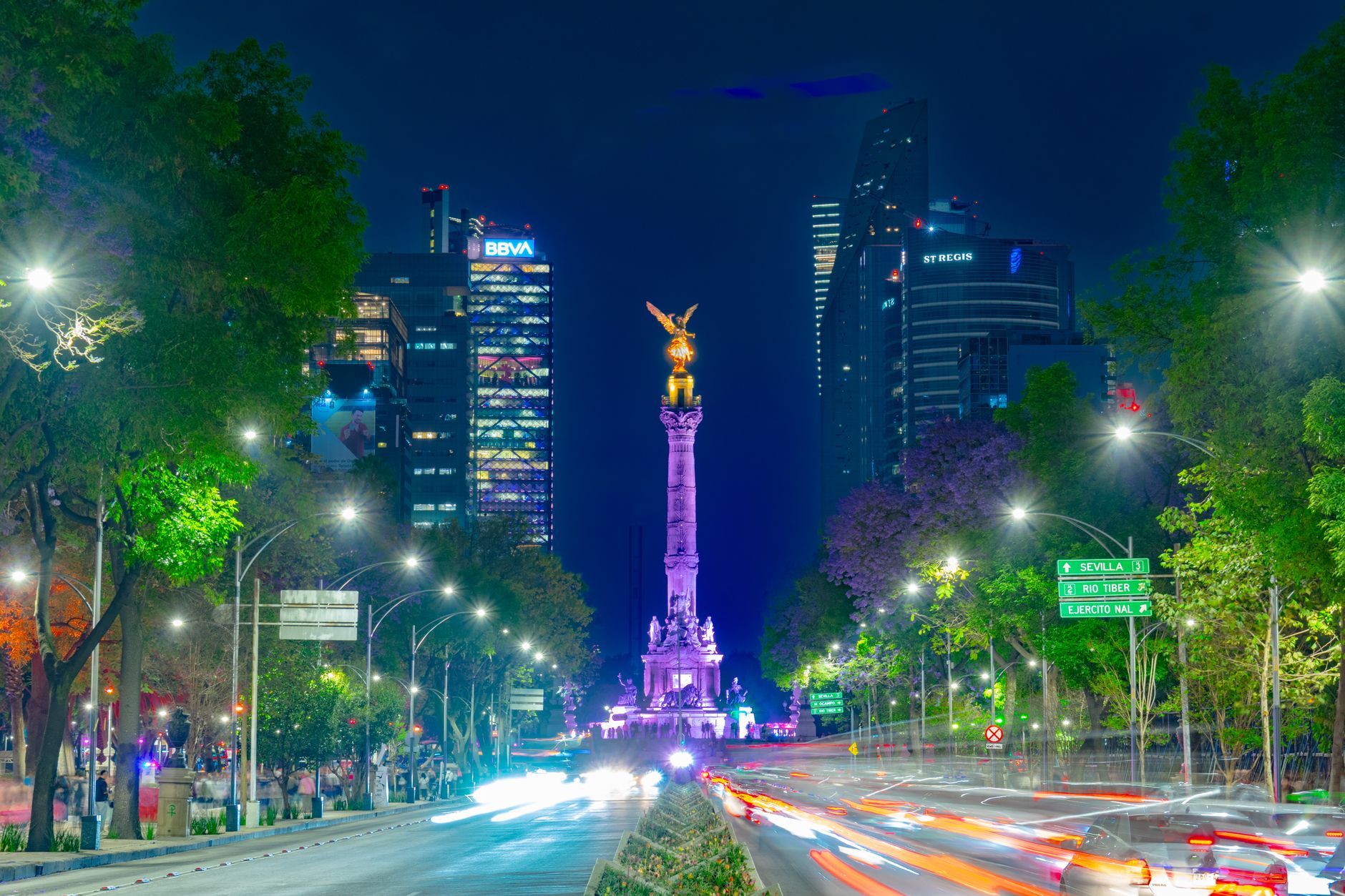 Vibrant night scene of the Angel of Independence monument in bustling Mexico City.