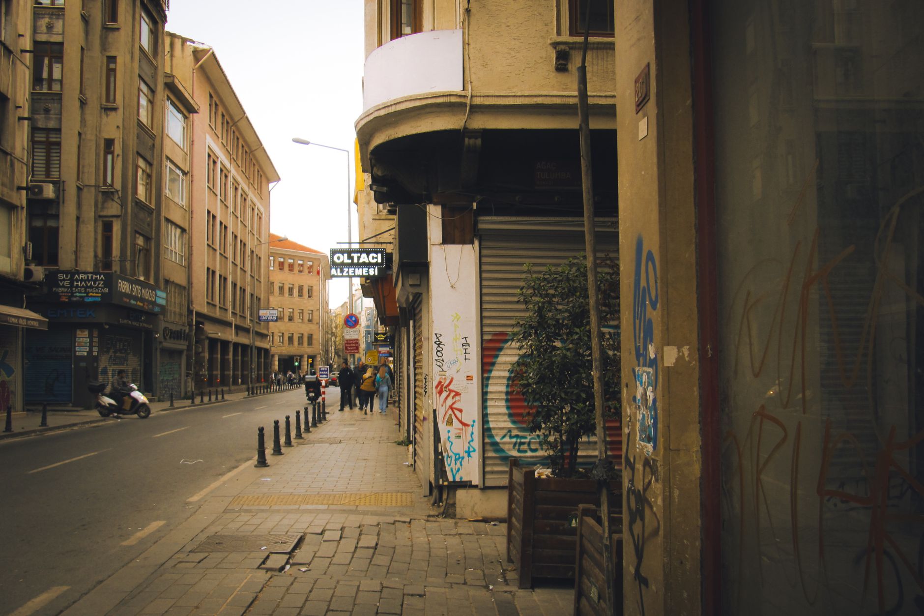 Bustling city street with graffiti-covered walls and people walking on the sidewalk.