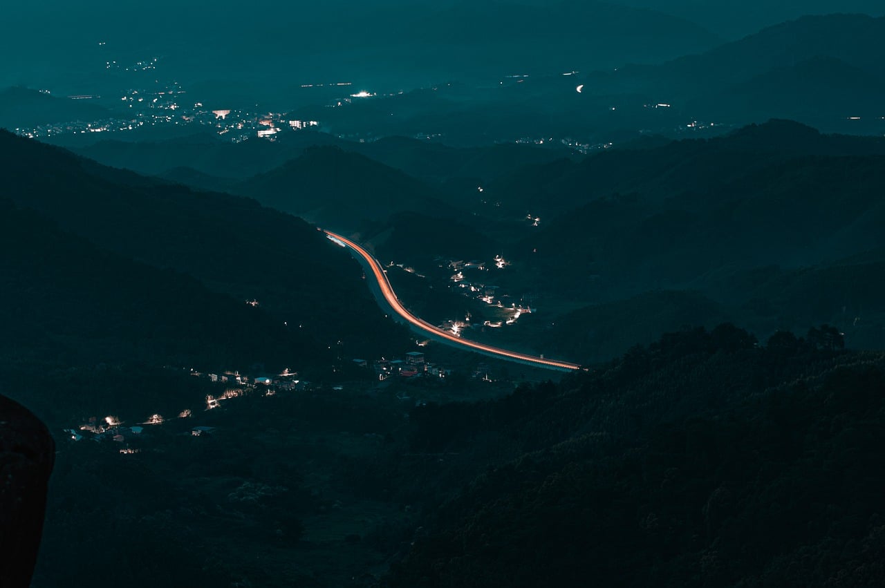 night landscape, mountains, highway, light trail, landscape at night, hilly area, city lights, road lights, panoramic shot, peaceful night, distant view, quiet landscape, long exposure, mountain silhouette, nature, small town, peaceful atmosphere, rural landscape, night driver, cityscape, quiet evening