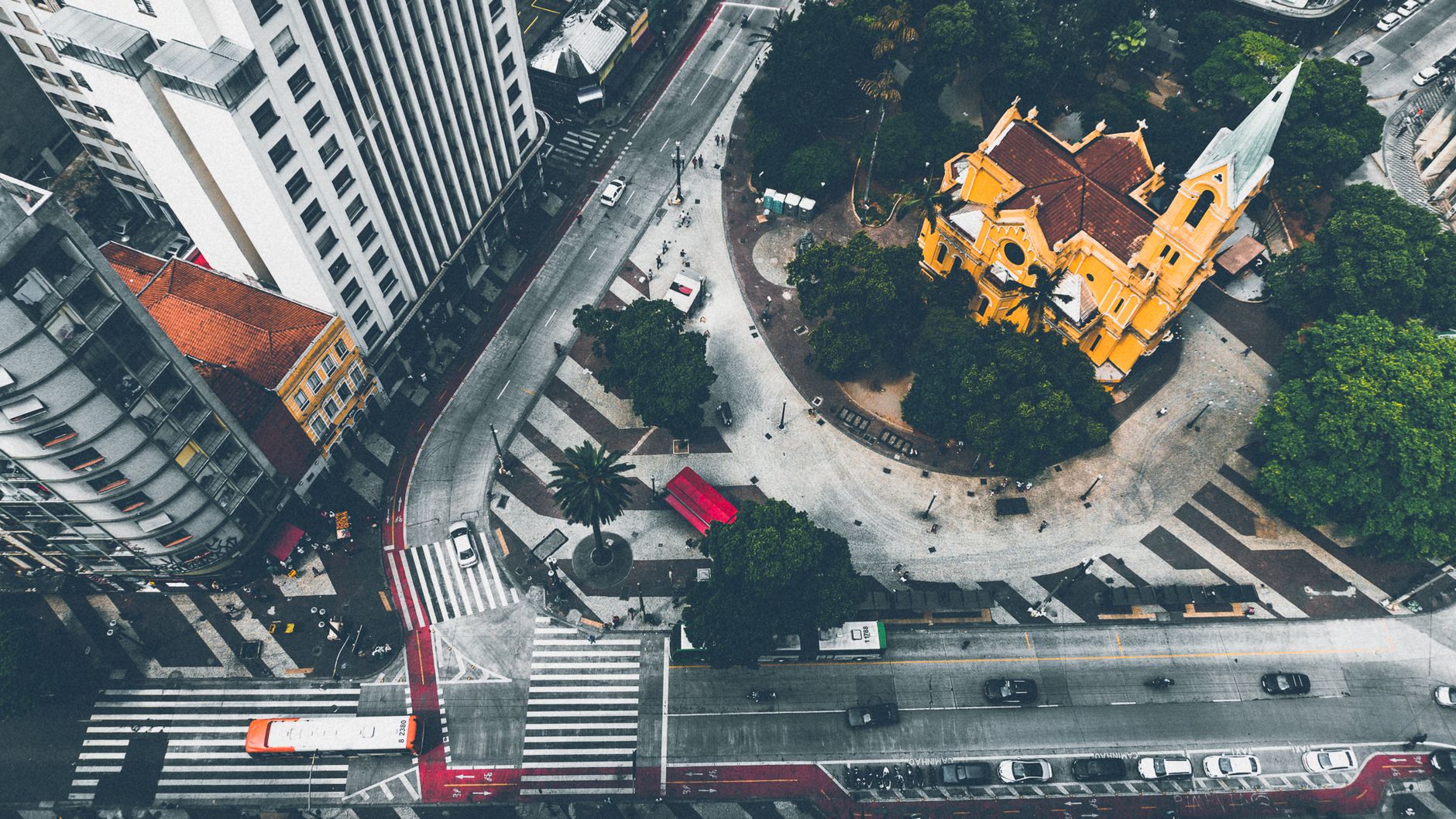 Top view of a bustling city intersection with a yellow church and traffic.