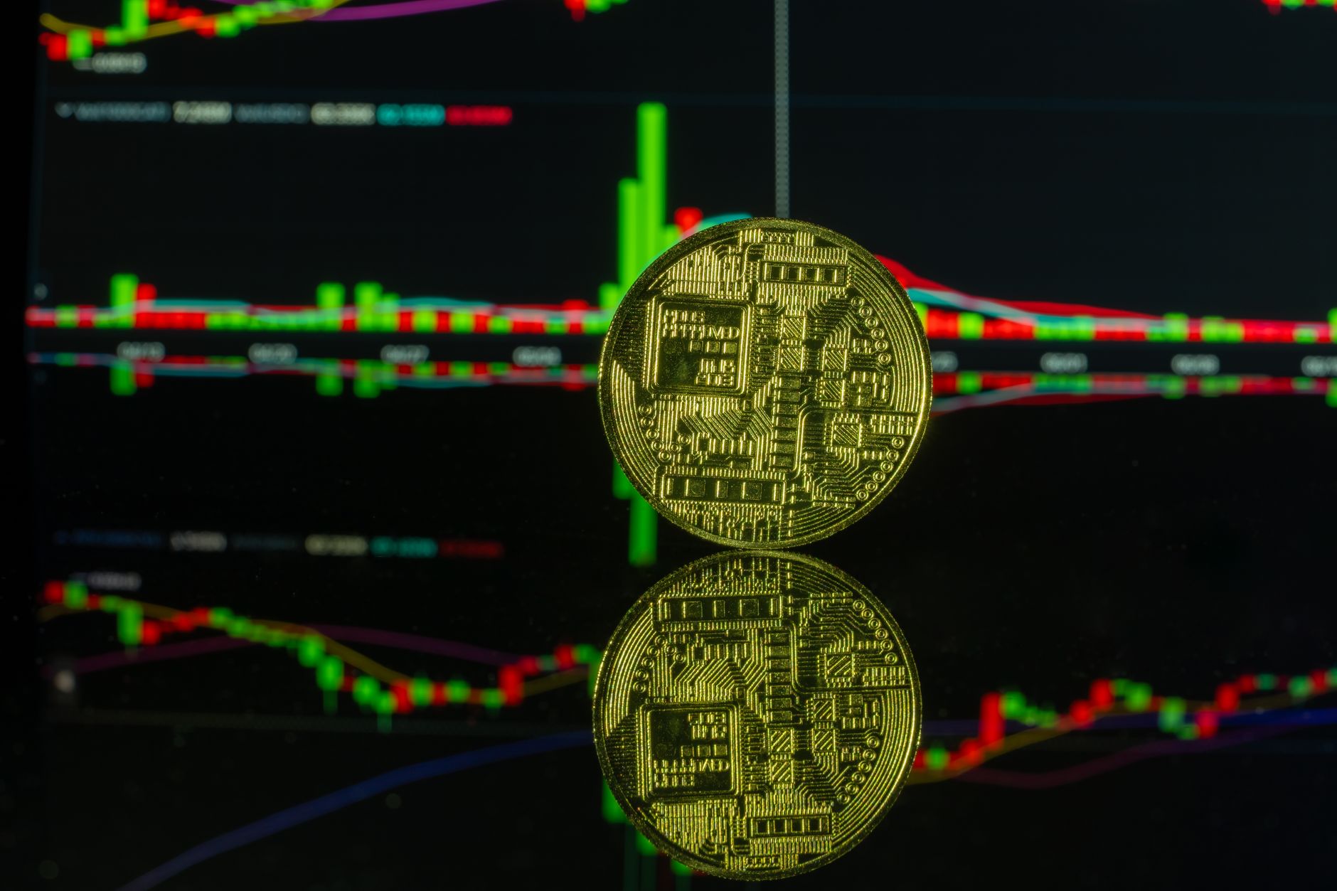 A gold cryptocurrency coin reflecting on a glass surface with colorful trading charts in the backdrop.