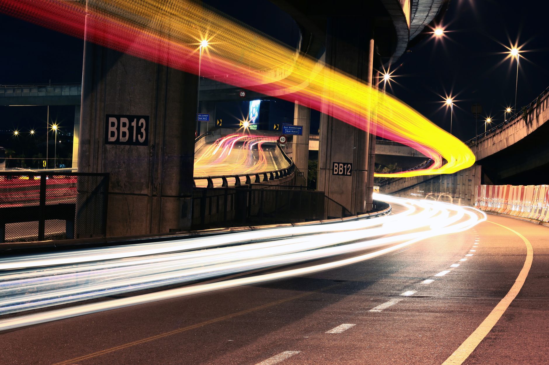 Dynamic urban scene at night showcasing colorful light trails on an expressway.
