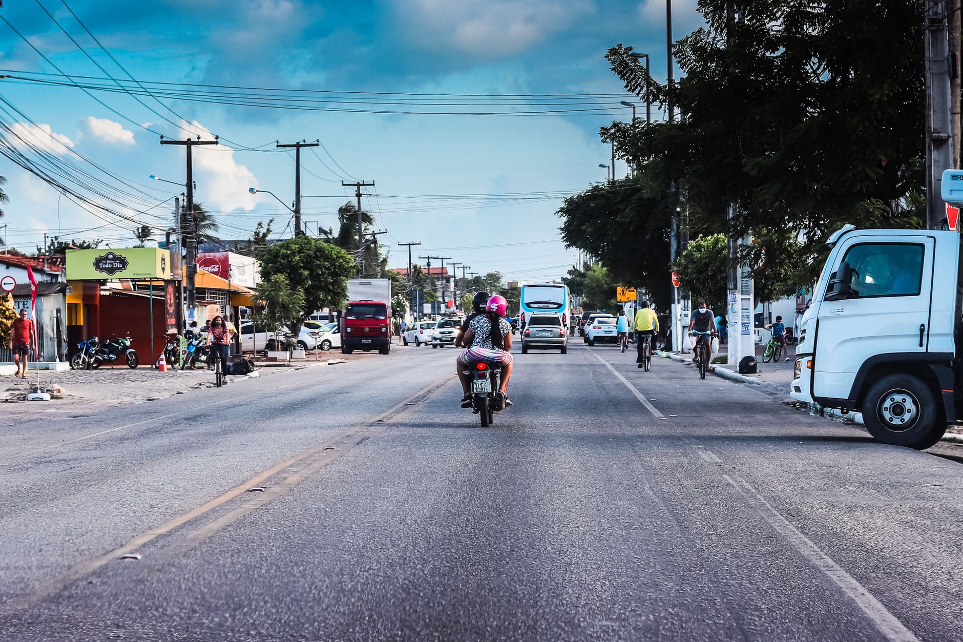 Motorcycles and vehicles on a bustling street in Paraíba, Brazil under a blue sky.