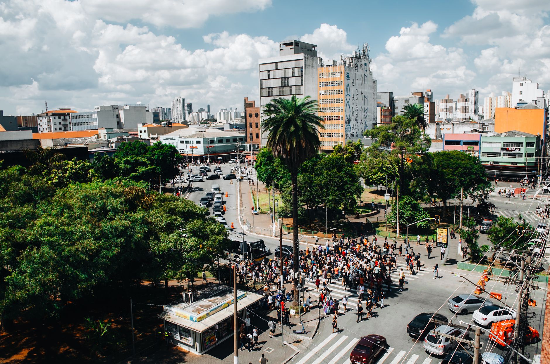 Aerial view of a busy urban intersection filled with people crossing the street under a clear sky.