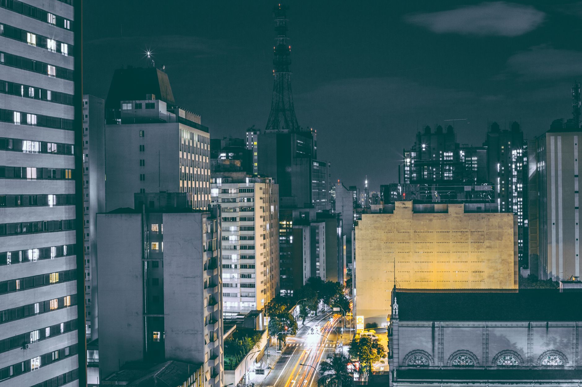 A vibrant cityscape at night with lit skyscrapers and bustling roads.