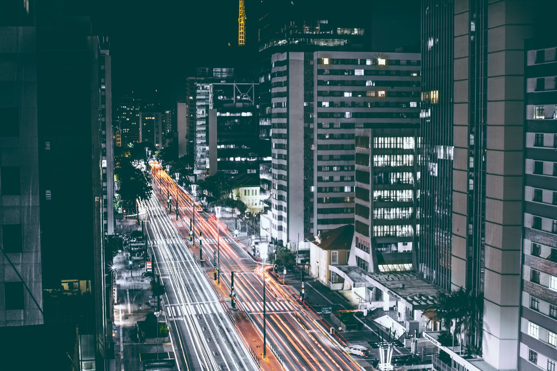 Dynamic city scene with light trails and skyscrapers at night, captured in a bustling urban environment.