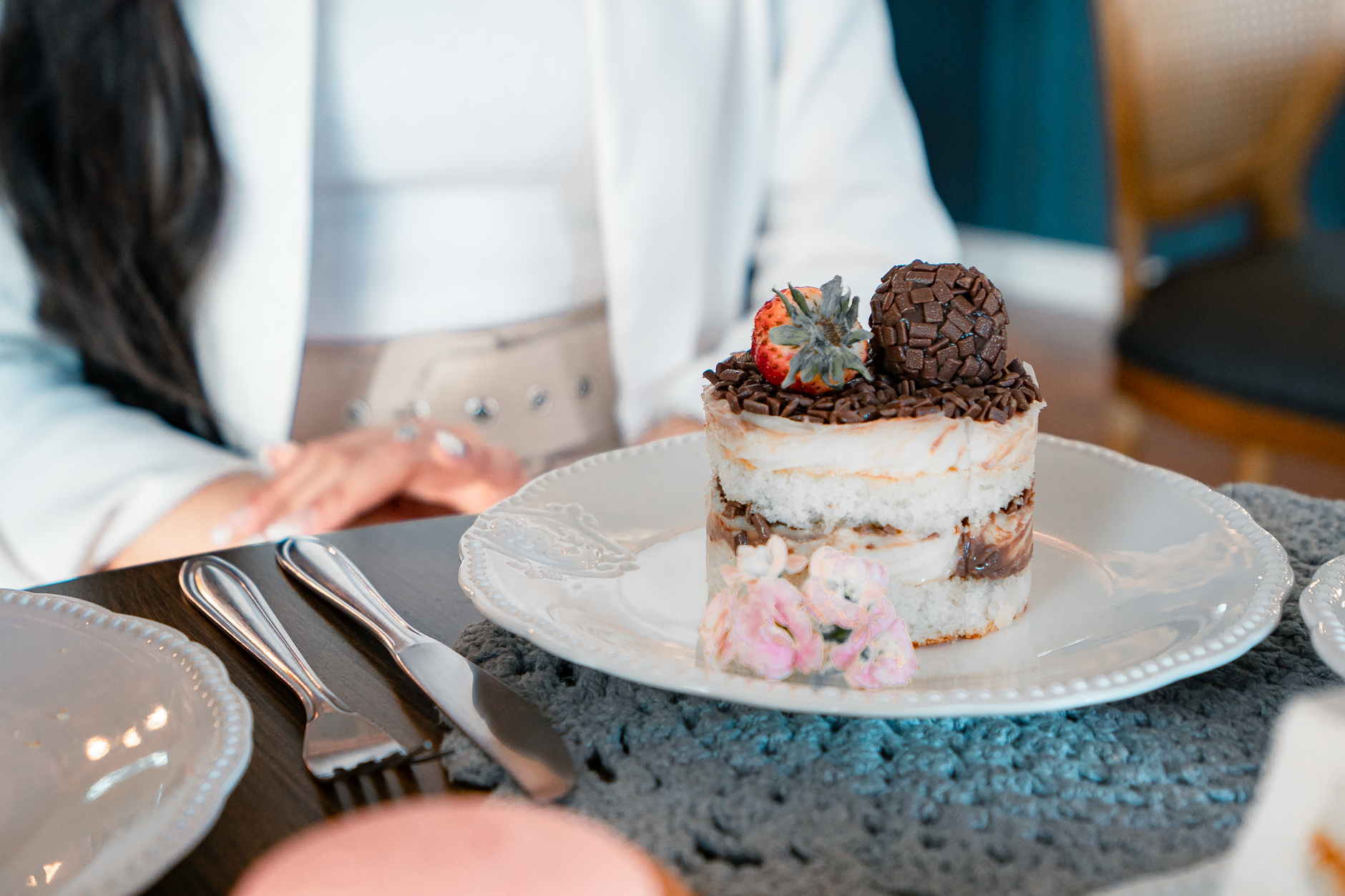 Close-up of a decadent dessert with chocolate and strawberry topping, set on an elegant table.