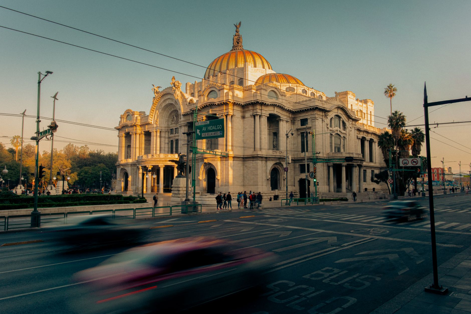 A scenic view of Palacio de Bellas Artes with traffic at sunset in Mexico City.