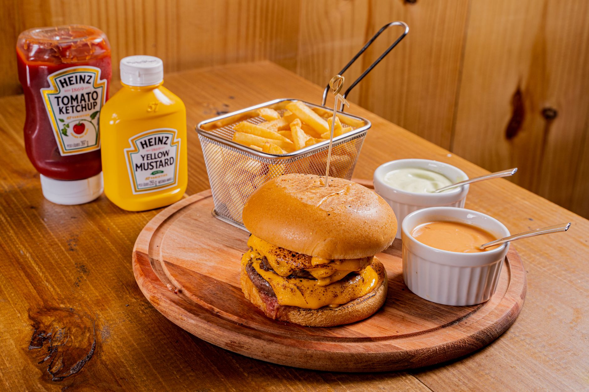Tasty beef burger with fries, ketchup, mustard, and sauces, perfect for a delicious lunch.