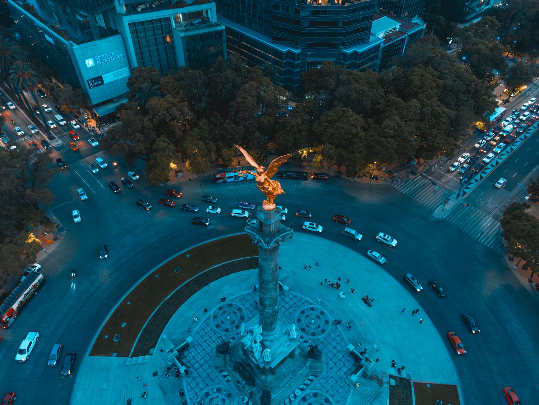 Stunning aerial drone shot of the Angel of Independence in Mexico City, capturing the vibrant urban landscape and traffic.