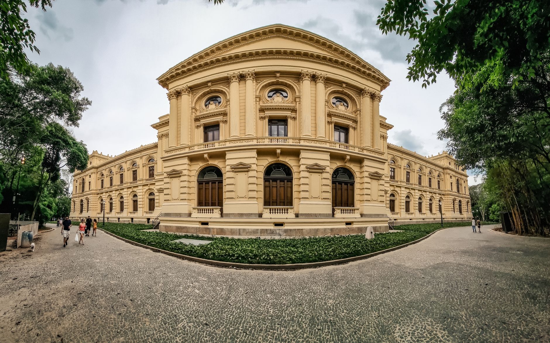 Panoramic view of historic architectural structure in São Paulo, surrounded by trees and visitors.