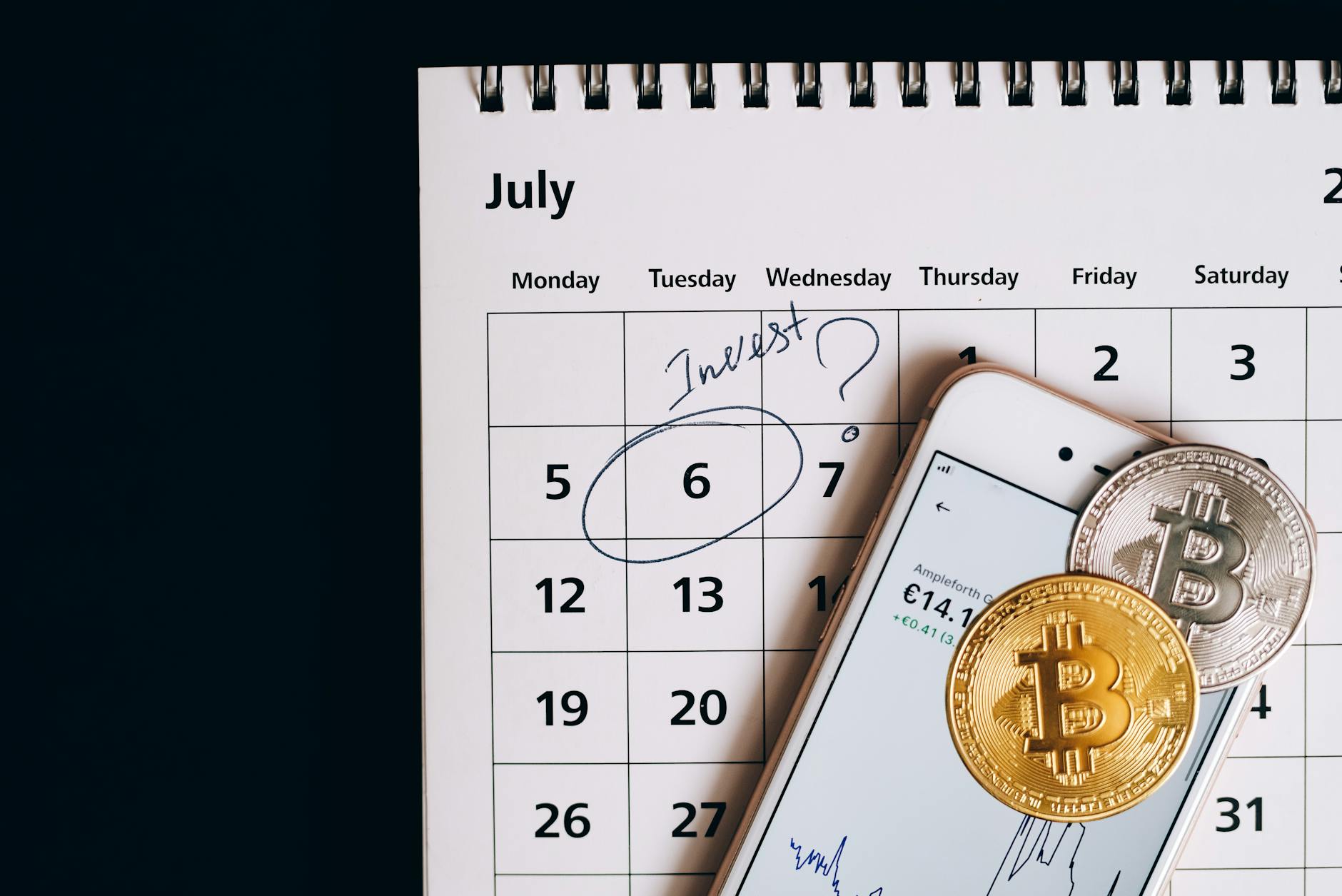 Smartphone with bitcoins on calendar, marking investment date.