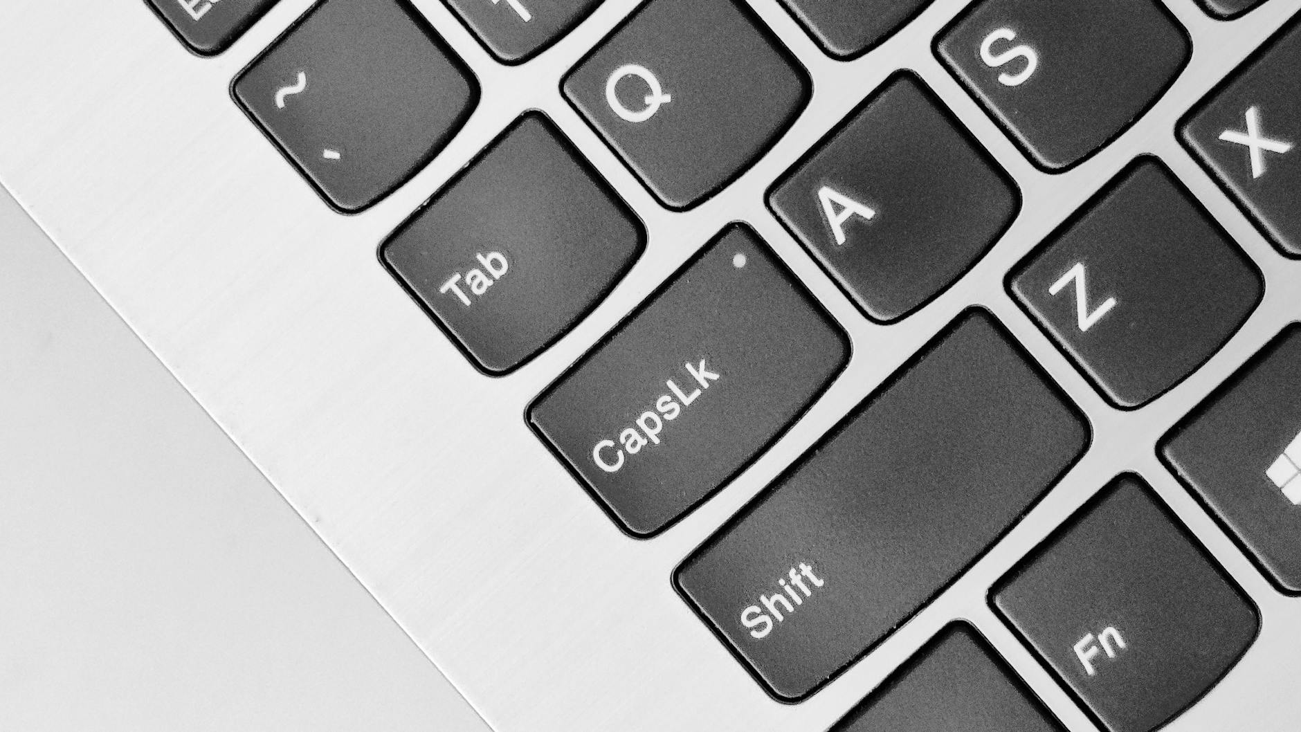 A detailed close-up of a laptop keyboard highlighting the Caps Lock and Shift keys.