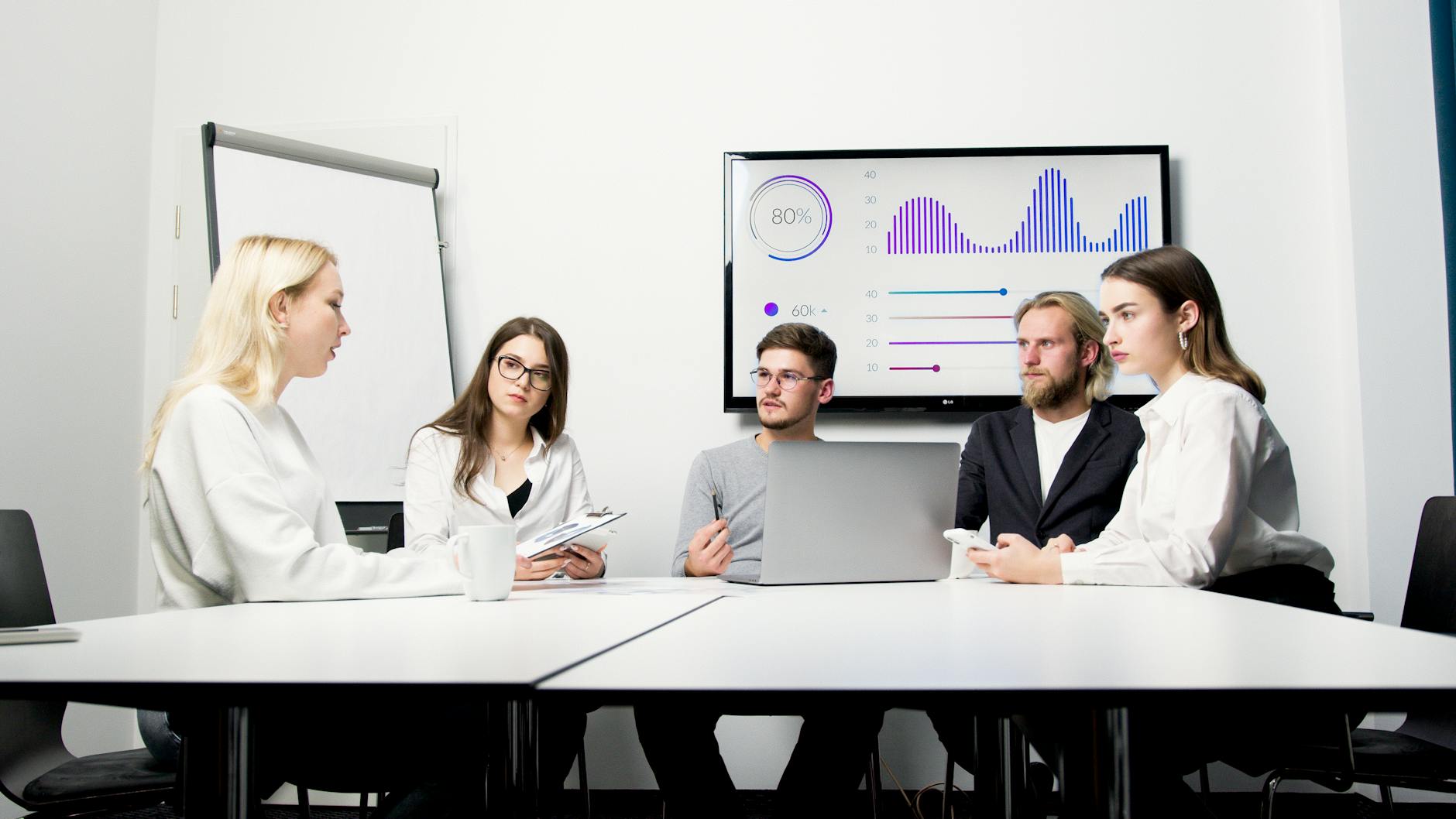 A group of professionals engaged in a business meeting with data presentation.