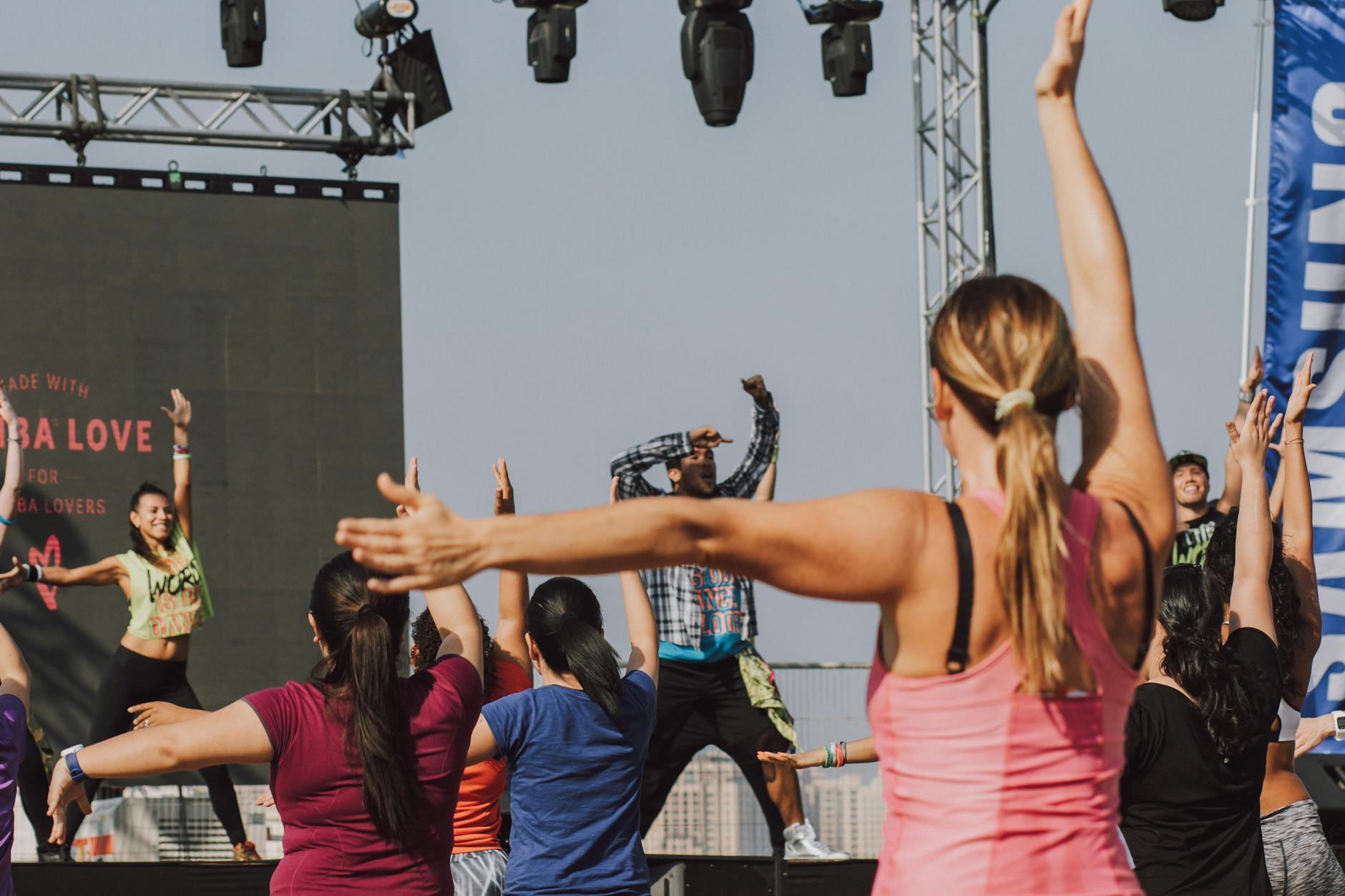 Group of people participating in an energetic outdoor Zumba session led by an instructor.