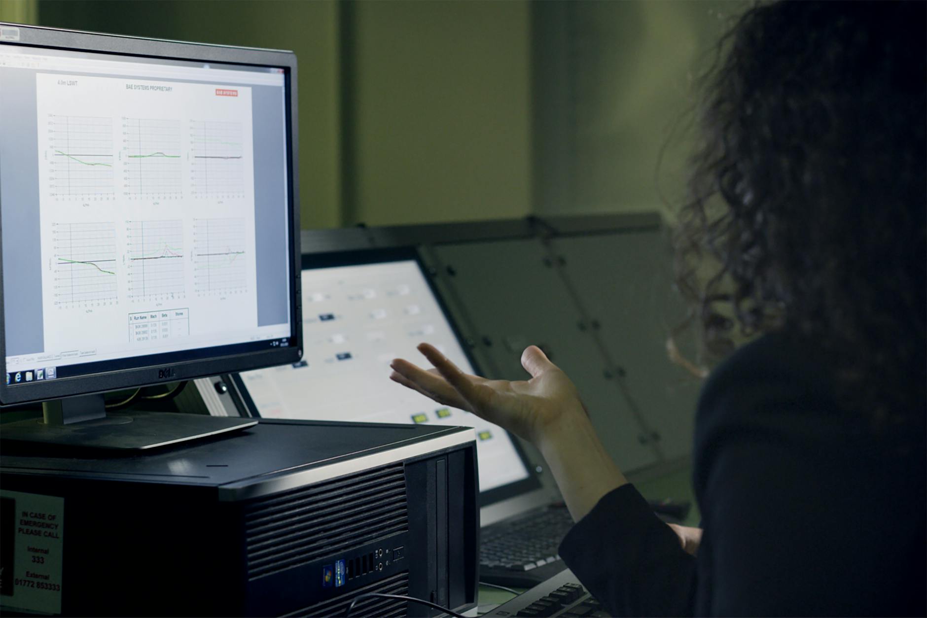 A woman analyzes data on a computer screen in a modern office setup, focusing on technological research.