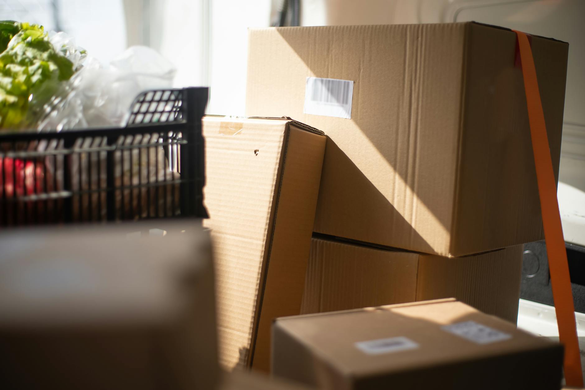 A collection of cardboard boxes inside a sunlit van, showcasing delivery logistics.
