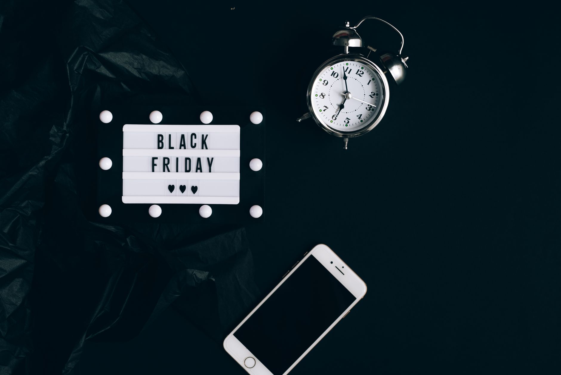 Stylish Black Friday promotion with alarm clock and smartphone on dark background.