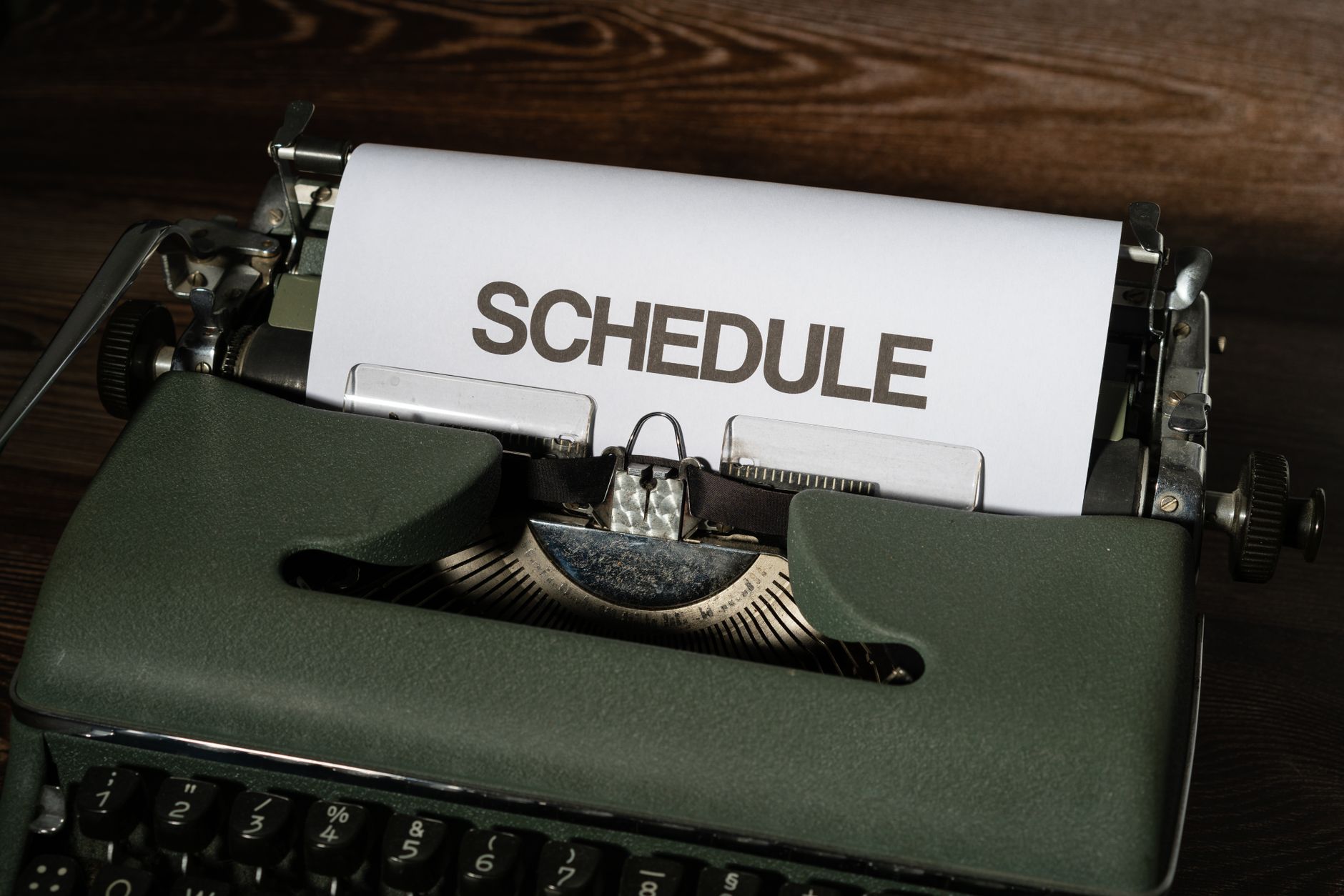 A vintage typewriter with the word 'SCHEDULE' typed on white paper, conveying planning.