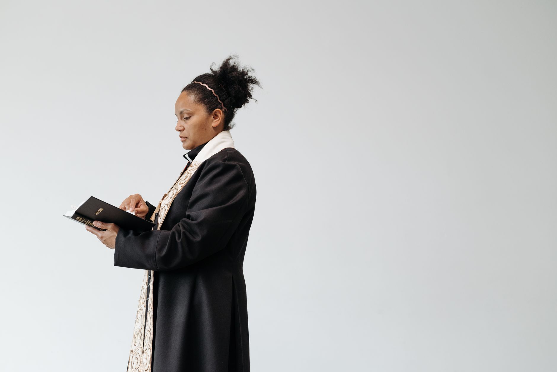 A female pastor reading a Bible indoors, showcasing faith and spirituality.