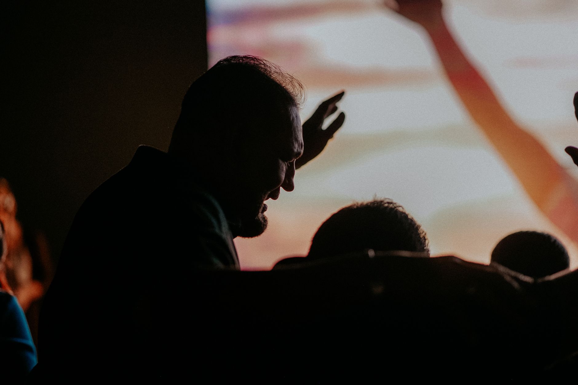 Silhouette of people with raised hands in worship, capturing emotion and devotion.