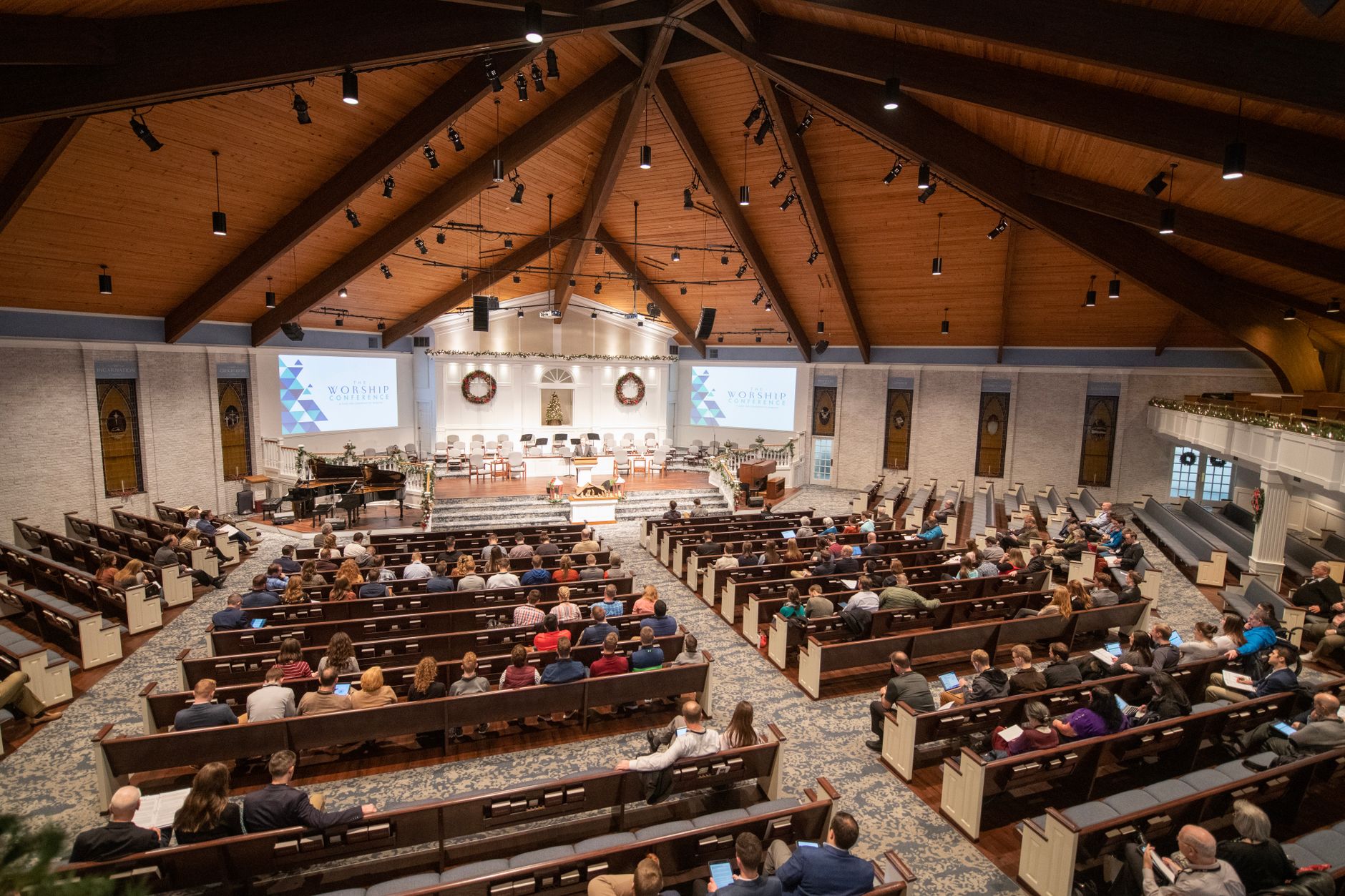 Large congregation gathered in church with wooden interiors, engaged in a service.