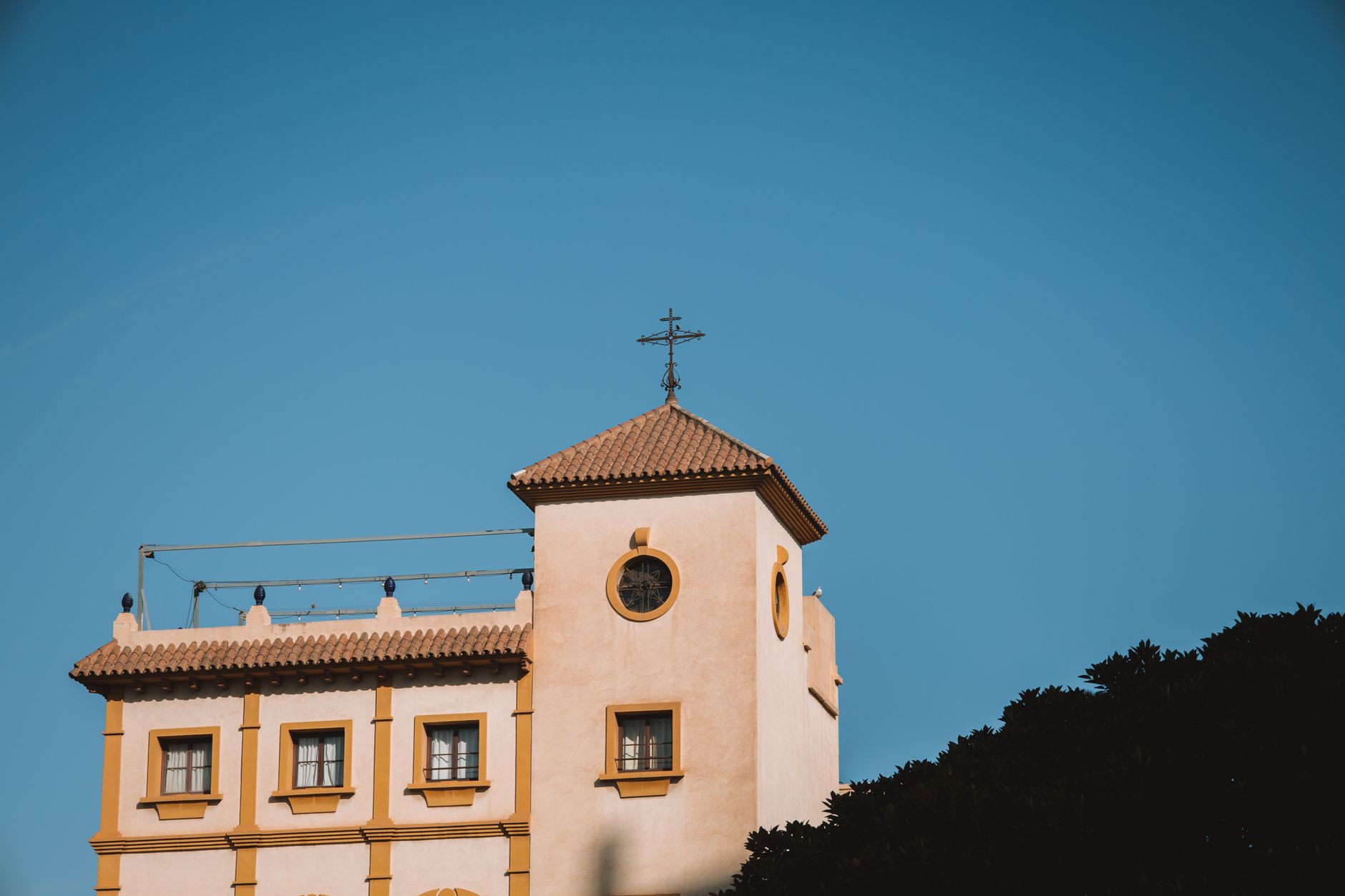 A picturesque church tower in Málaga, Spain, with clear blue skies, showcasing classic architecture.