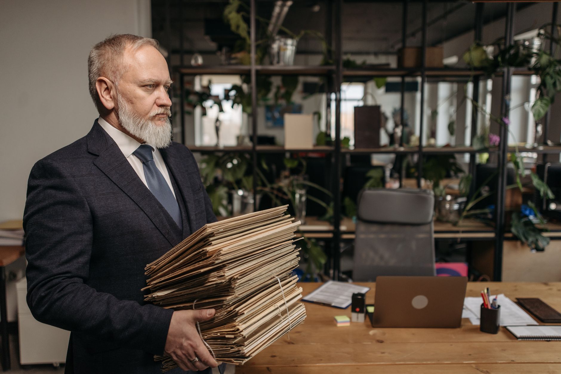Senior businessman holding files in a modern office setting, embodying dedication and professionalism.