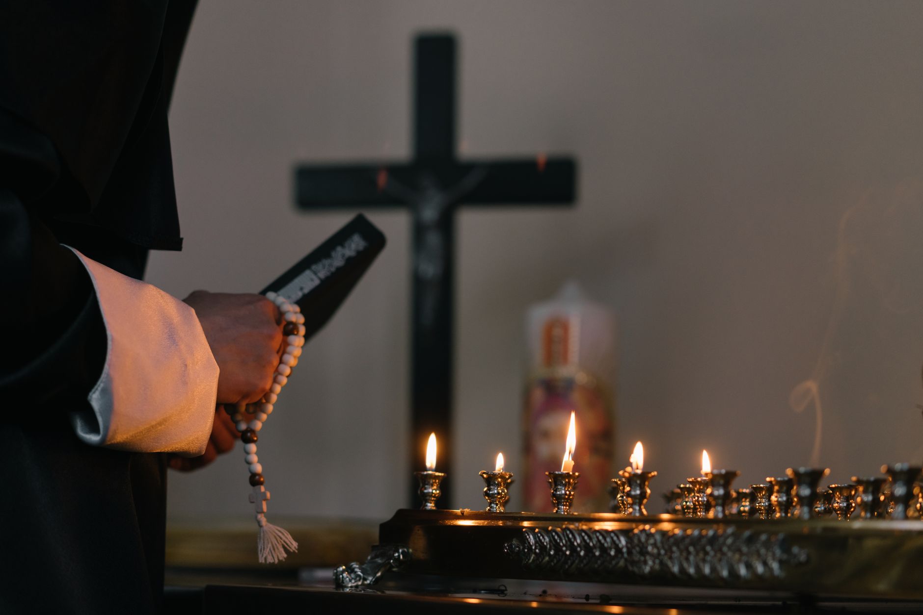 Serene religious setting with candles, cross, and prayer beads symbolizing faith and meditation.