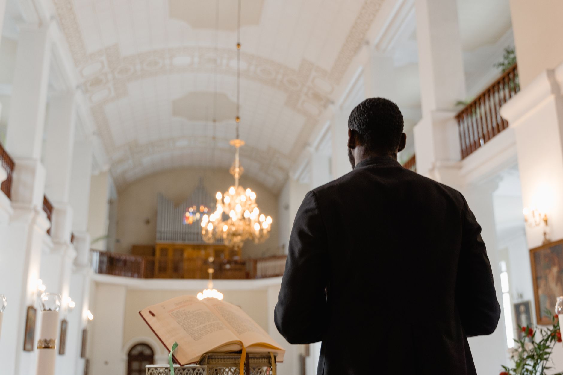 A priest delivering a sermon in a beautifully ornate church interior.