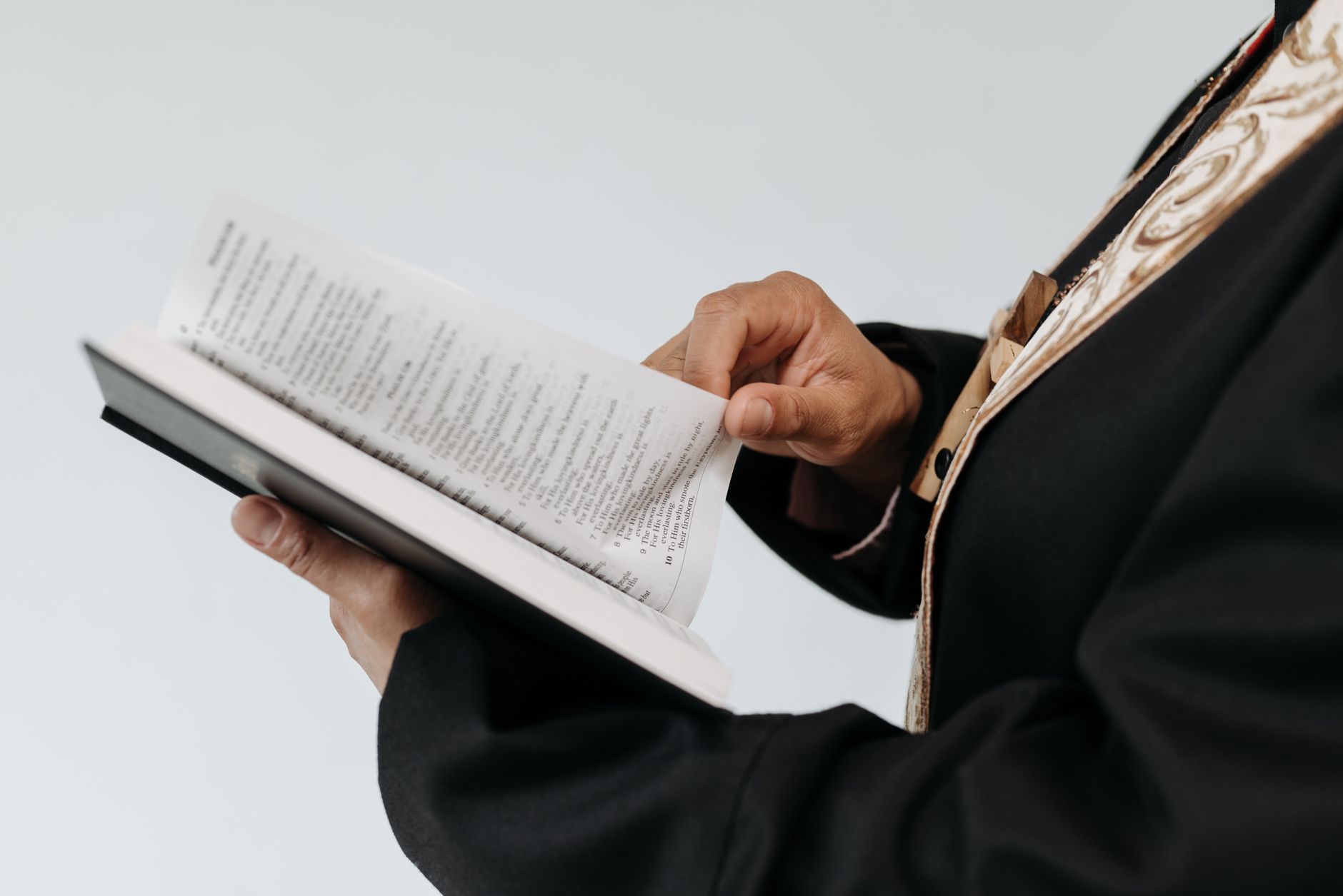 Close-up of a priest reading from a Bible book during a religious service.
