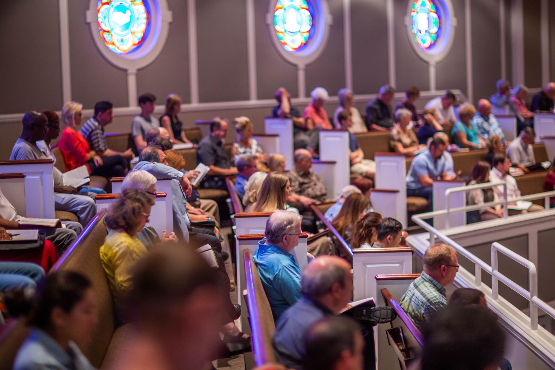 An engaged audience seated inside a church, with visible stained glass windows enhancing the ambiance.