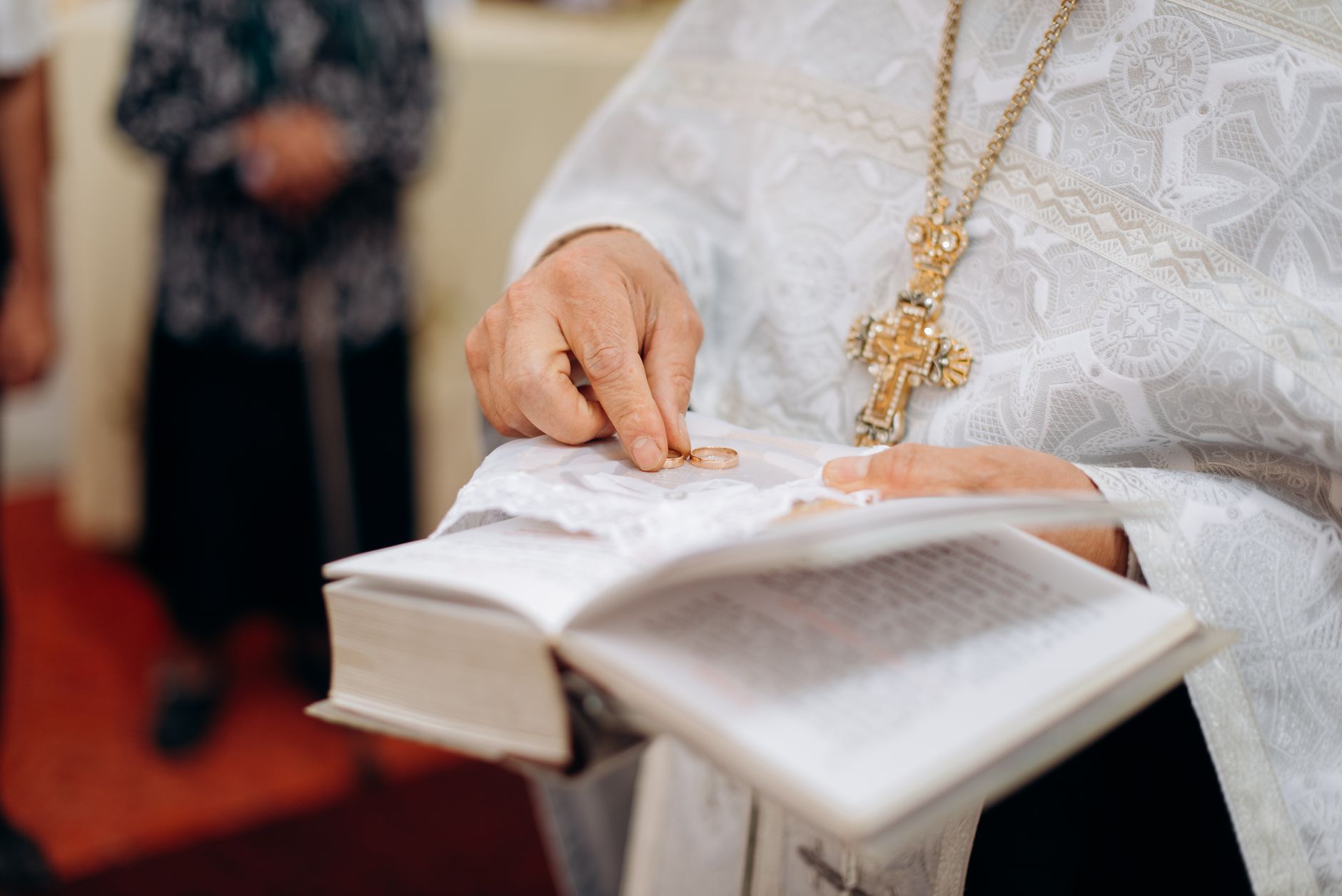 A priest holding a book with a cross during a religious ceremony, symbolizing faith and devotion.