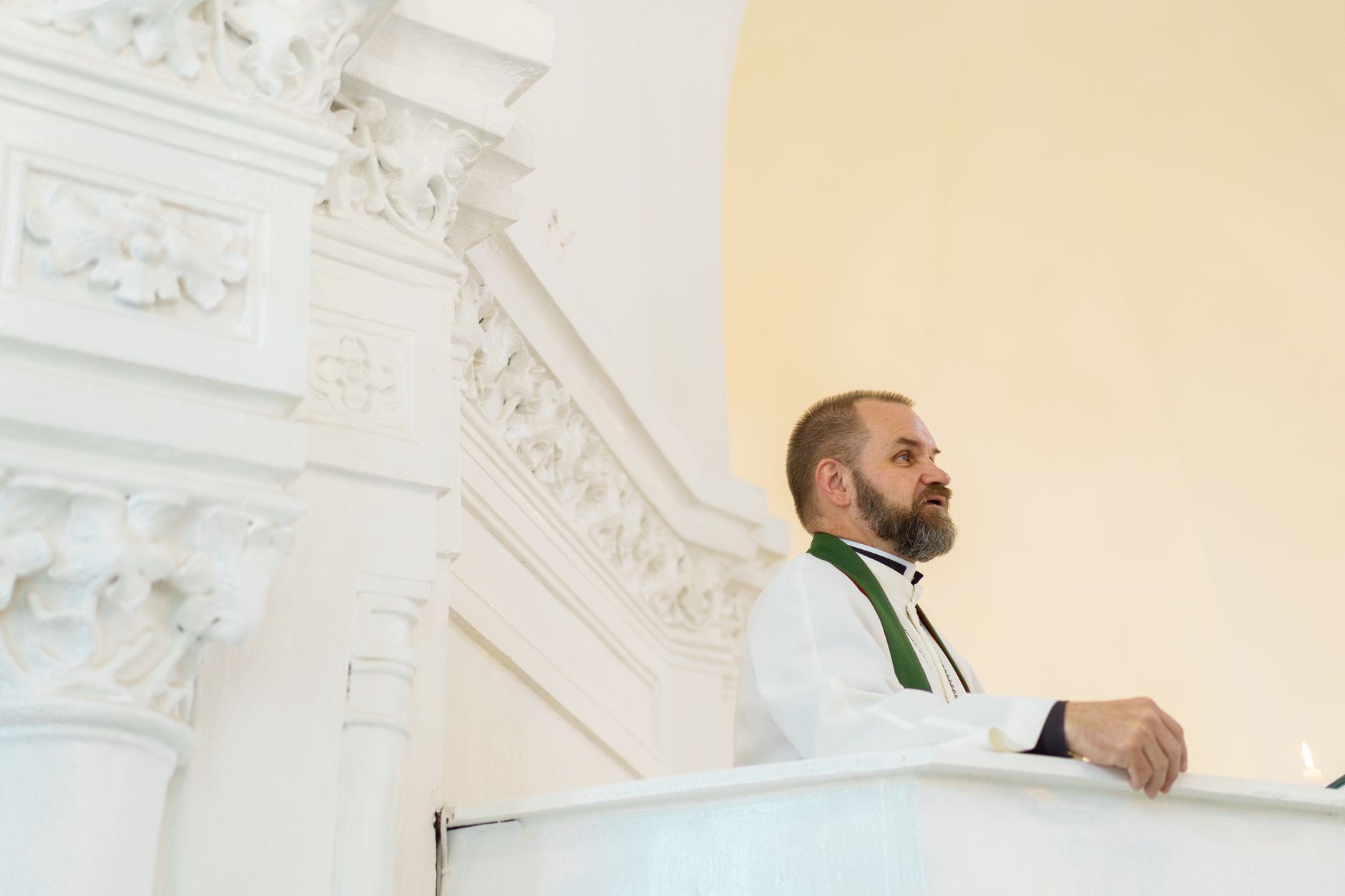 A pastor stands in a bright church, delivering a sermon from the altar.