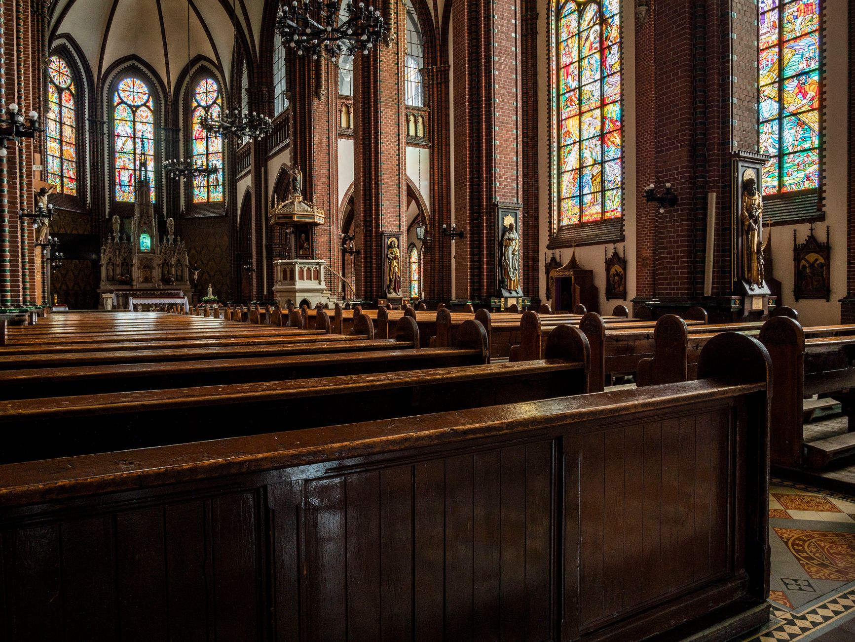 Empty church interior with stained glass and wooden pews.