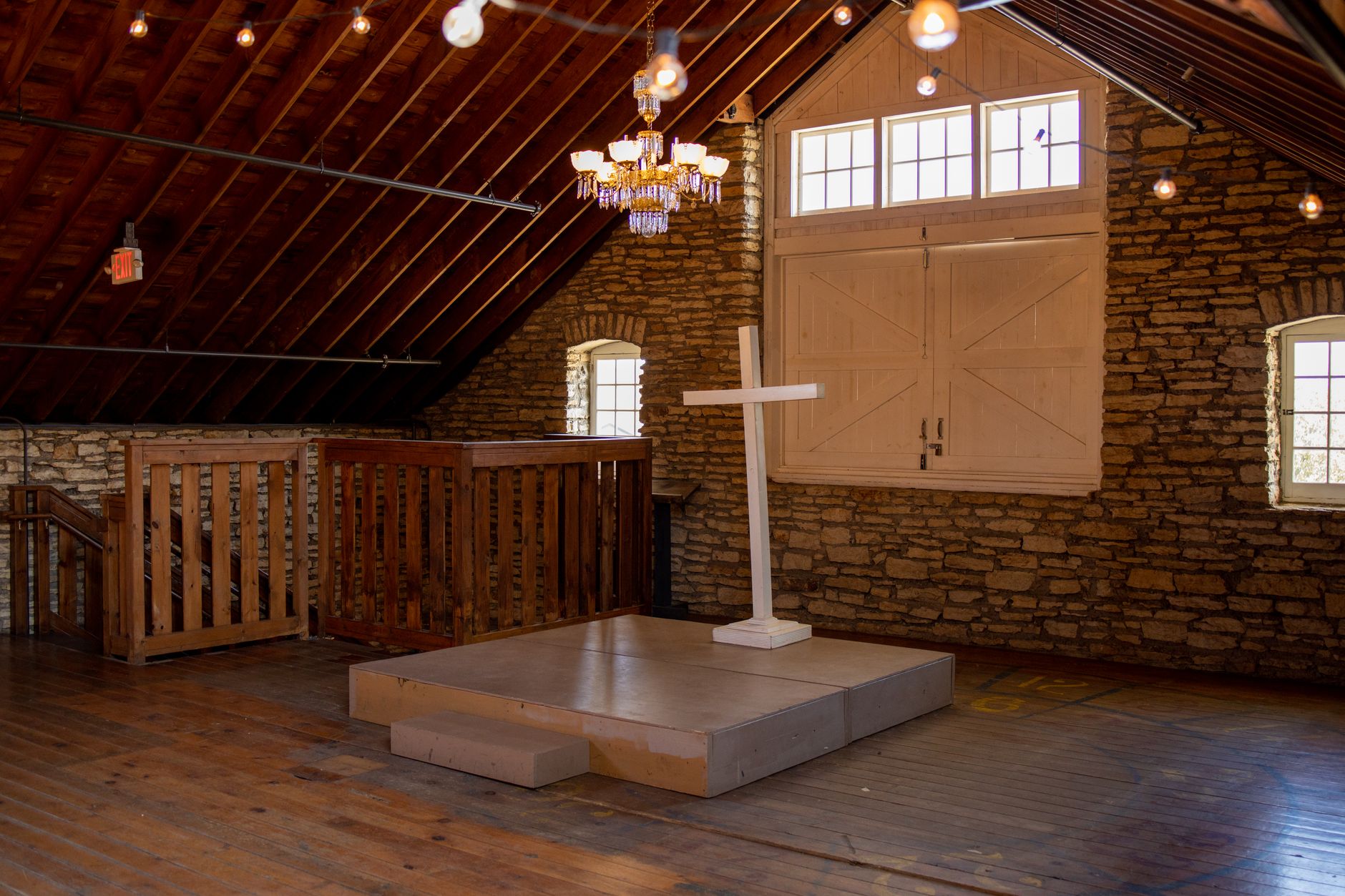 Elegant wooden chapel interior in Rochester, MN, featuring a cross, chandelier, and natural light.