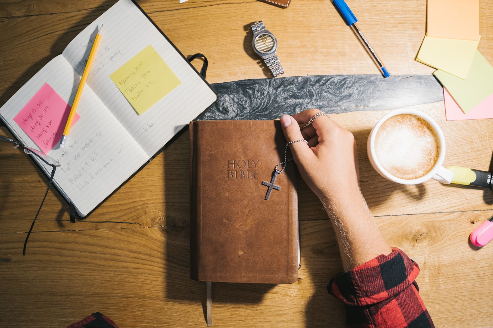 Top view of Bible study setup with coffee, notes, and wooden table.