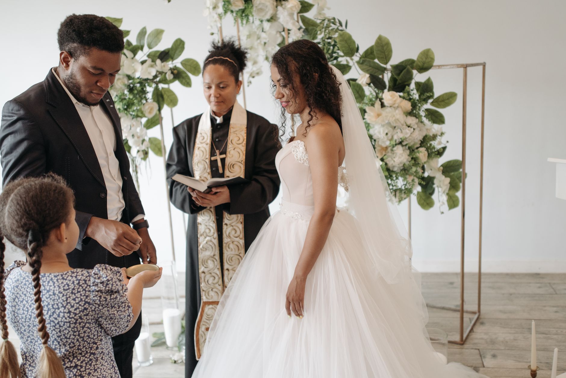 A beautiful indoor wedding ceremony with bride, groom, and officiant exchanging vows.