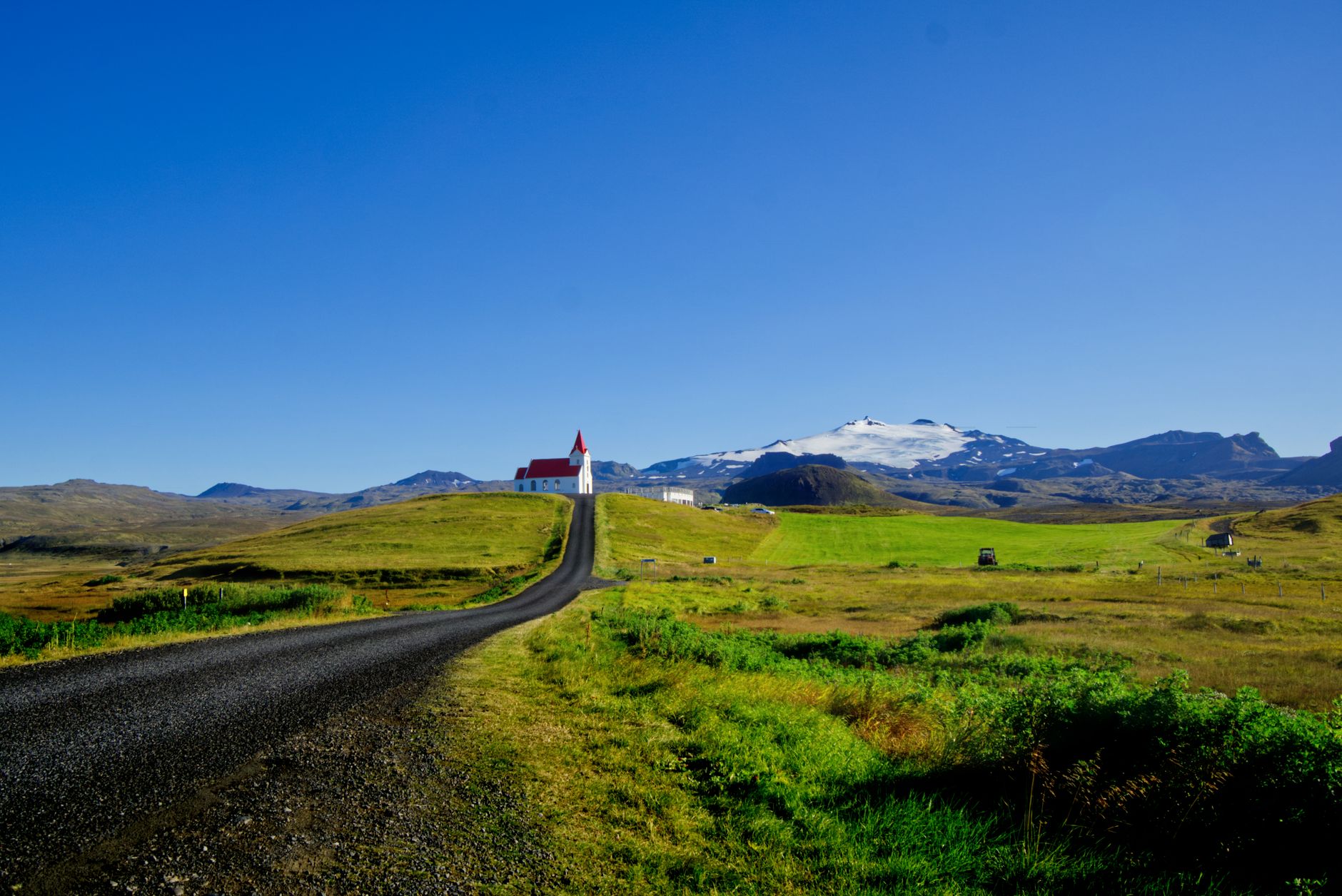 Discover the serene beauty of Iceland's Snæfellsbær with its scenic church and majestic mountains under a blue sky.