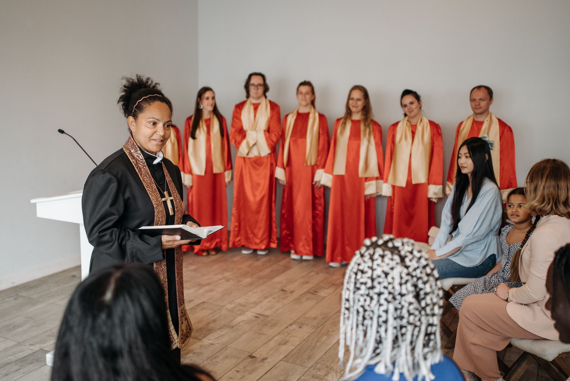 Pastor leading a church service with choir and congregation in attendance.