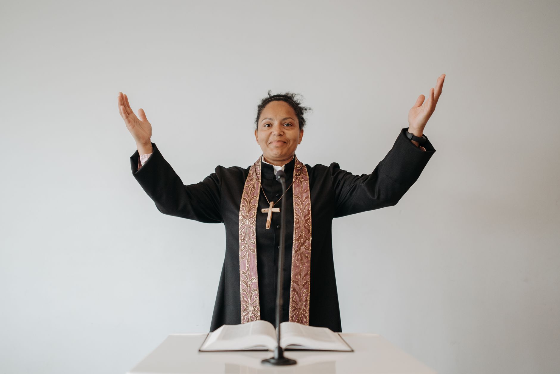 African American pastor with raised hands delivering a sermon in church.