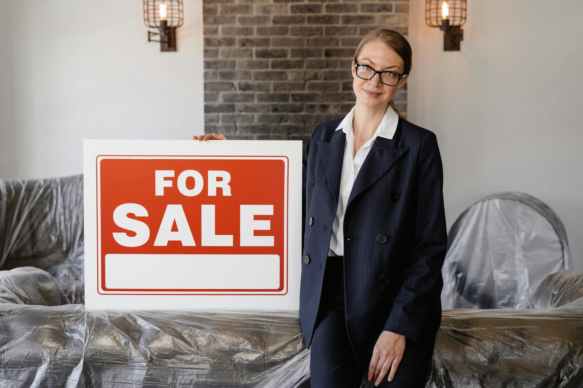 Smiling real estate agent standing outdoors with a sold sign, symbolizing success and achievement in property sales.