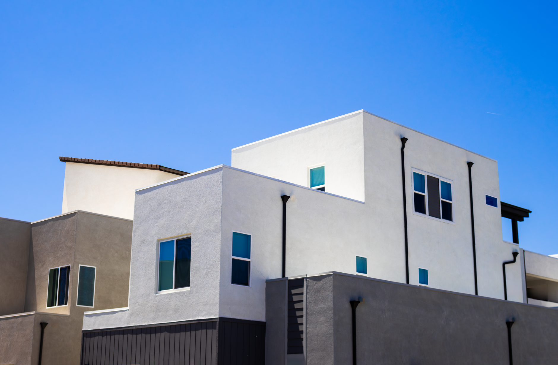 Contemporary apartment building exterior with balconies under a bright blue summer sky.