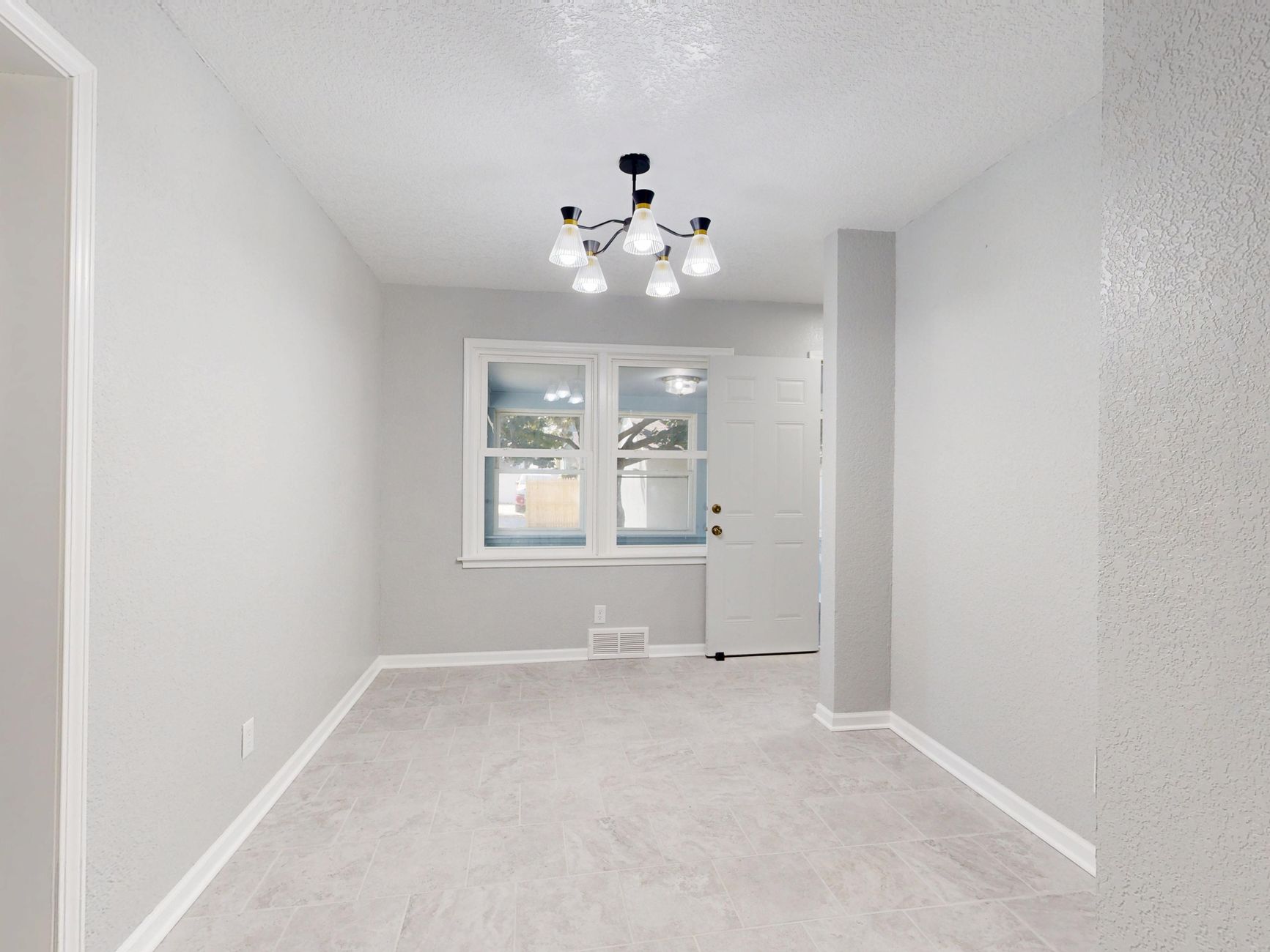 A spacious, empty room with a modern light fixture and large windows showcasing a minimalist design.